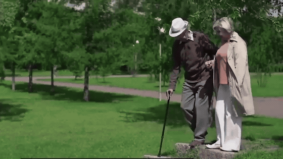 An older couple taking the steps slowly in the park